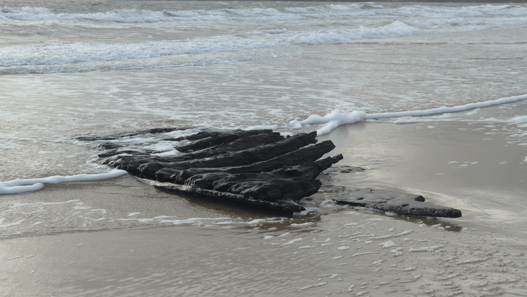 Photo of high tide at Studland Bay with historic timbers revealed on the shoreline. Believed to be a section of hull from the 17th century merchant ship the Fame of Hoorn or the Swash Channel wreck